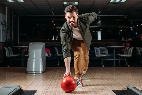 Šťastný Mladý Muž Házet Bowlingovou Kouli Při Pohledu Fotoaparát — Stock fotografie