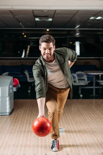 Glücklicher Junger Mann Wirft Bowlingball Auf Club — Stockfoto