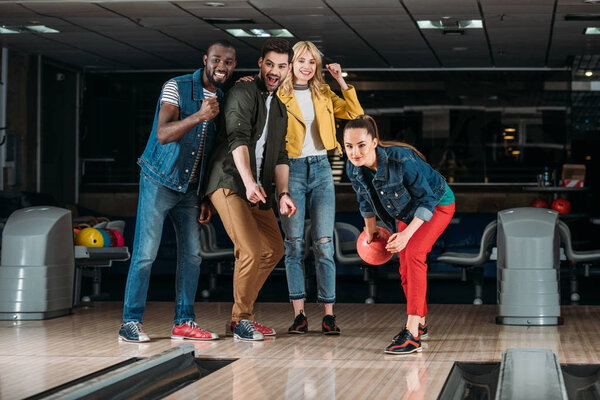 excited group of young friends playing bowling together