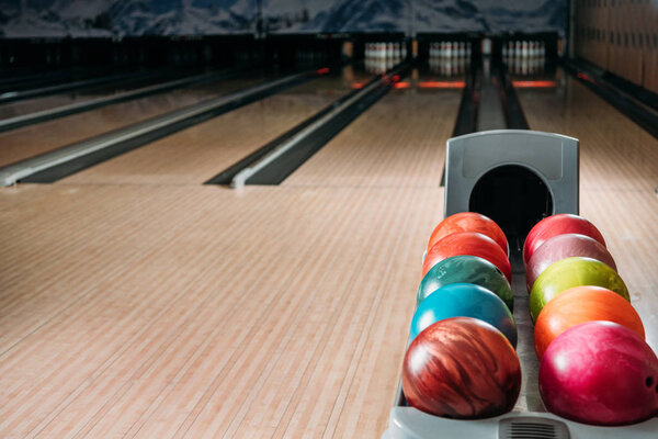 stand with colorful bowling balls in club in front of alleys
