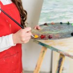 Zugeschnittenes Bild eines Kindes, das in der Werkstatt der Kunstschule Farbe aus der Palette nimmt