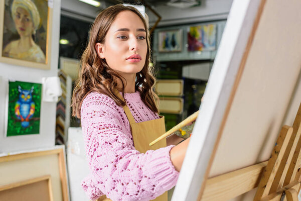attractive female artist painting in workshop