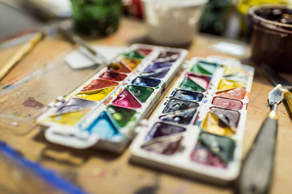 poster paints and watercolor paints on wooden table in workshop