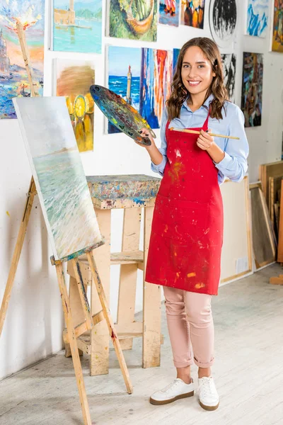 Bela Artista Feminina Segurando Pincel Pintura Paleta Perto Lona Oficina — Fotografia de Stock