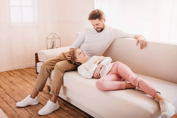 Entzückendes kleines Mädchen mit glücklichem Vater zusammen auf dem heimischen Sofa — Stockfoto