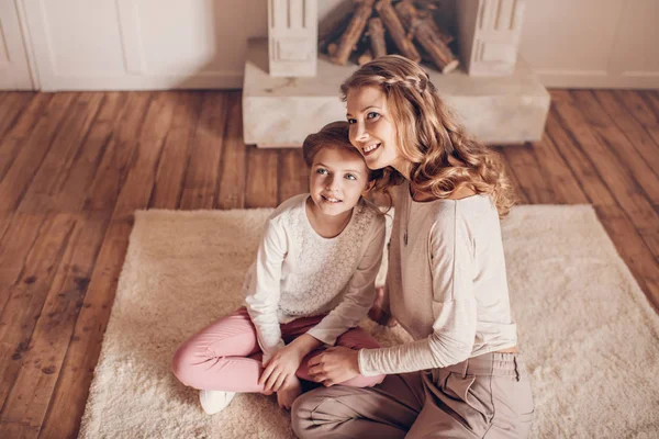 Вид под высоким углом счастливой матери и дочери, сидящих вместе на ковре и отводящих взгляд — Stock Photo