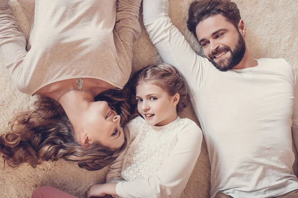 Вид зверху на щасливу сім'ю з однією дитиною, що лежить разом на килимі — стокове фото
