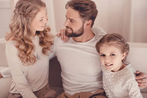 Familia joven y feliz con un niño sentado abrazándose juntos en casa - foto de stock