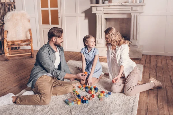 Família feliz brincando com construtor e sentado no chão em casa — Fotografia de Stock