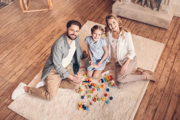 Glückliche Familie spielt mit dem Bauunternehmer und sitzt zu Hause auf dem Boden — Stockfoto