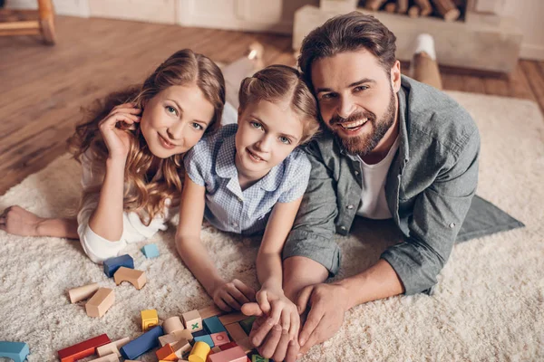 Glückliche Familie spielt mit Bauarbeiter und liegt zu Hause auf dem Boden — Stockfoto