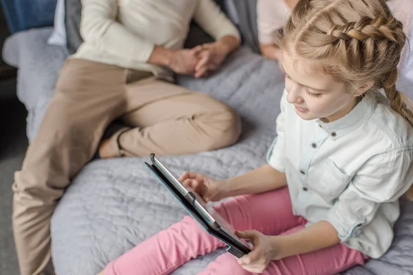Entzückende Tochter nutzt digitales Tablet und liegt mit ihren Eltern im Bett — Stockfoto