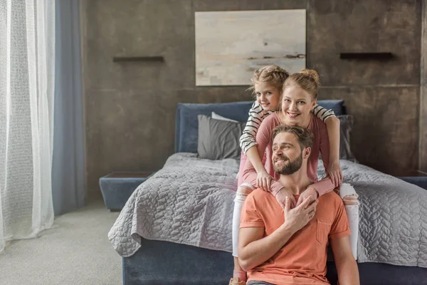 Joyeux jeune famille avec un enfant assis ensemble et étreignant dans la chambre — Photo de stock