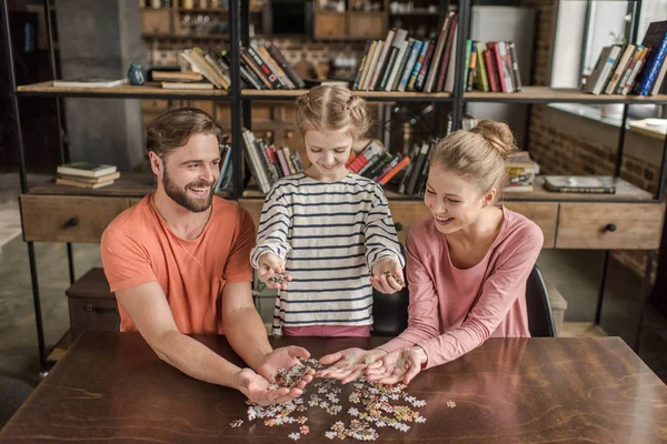 Família feliz com uma criança brincando com quebra-cabeças em casa — Fotografia de Stock