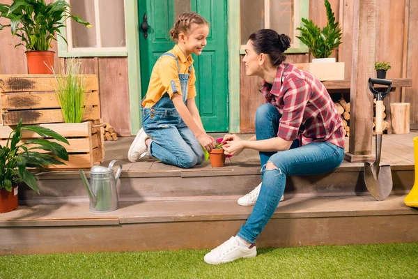 Glückliche Mutter und Tochter sitzen zusammen auf der Veranda und pflanzen Pflanzen an — Stockfoto