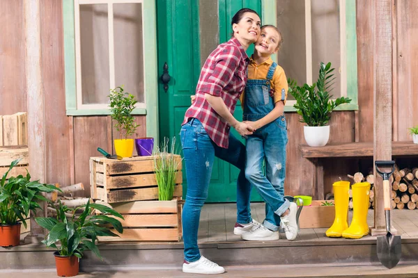 Happy mother and daughter standing together and holding hands on porch — Stock Photo