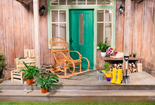 Potted plants and rocking chair on porch with gardening tools — Stock Photo