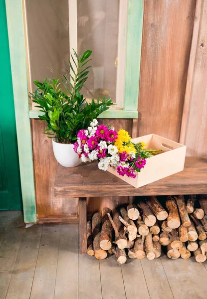 Vista de cerca de la planta y las flores en caja de madera en el banco en el porche - foto de stock