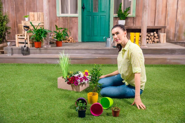 Atractivo jardinero con plantas y macetas sentadas sobre hierba verde - foto de stock