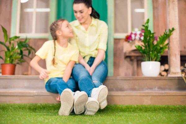 Happy mother and daughter sitting on porch and hugging outdoors — Stock Photo