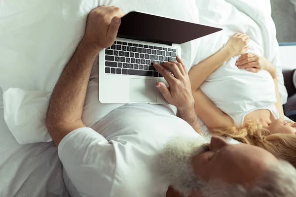 Casal maduro na cama com laptop — Fotografia de Stock