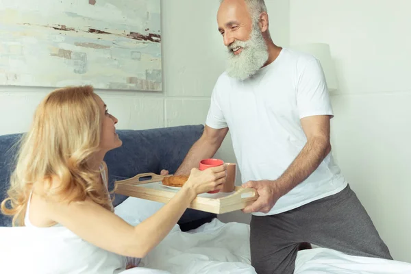 Mature couple with breakfast in bed — Stock Photo