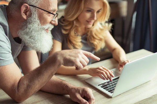 Pareja de mediana edad trabajando juntos en el ordenador portátil - foto de stock