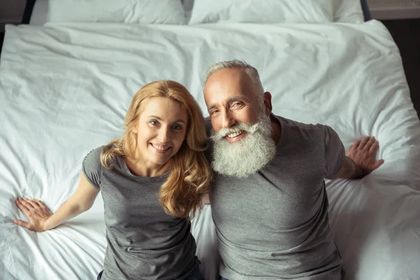 Paar mittleren Alters sitzt auf Bett — Stockfoto