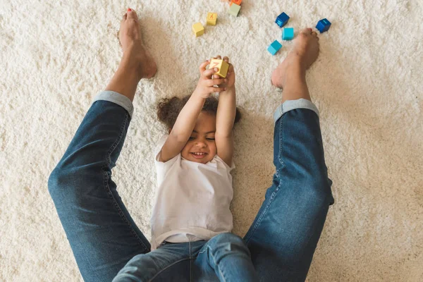 Kid girl playing with mother on carpet — Stock Photo