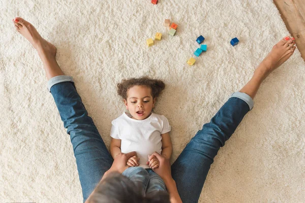 Niña jugando con la madre en la alfombra - foto de stock
