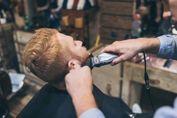 Barber trimming customers beard — Stock Photo