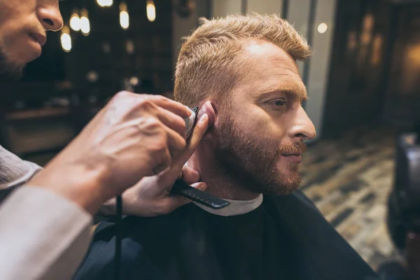 Barbier coupe les cheveux du client — Photo de stock