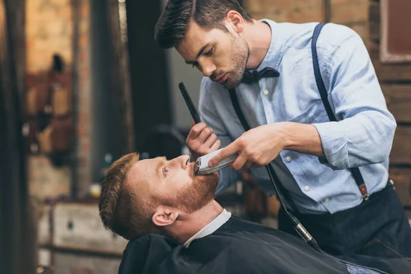 Barber trimming customers beard — Stock Photo