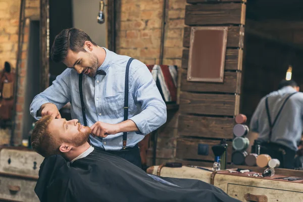 Barber trimming customers beard — Stock Photo