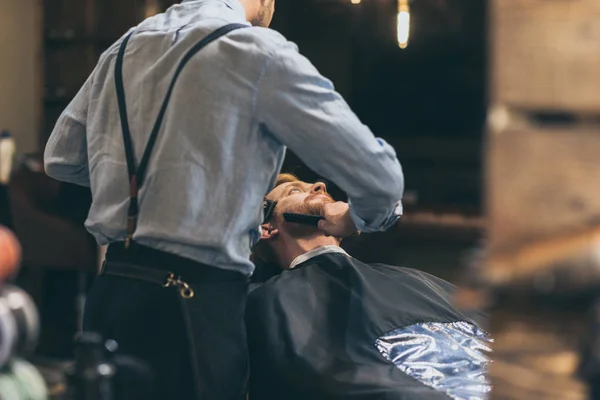 Barber trimming customers beard — Stock Photo