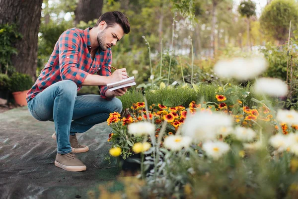 Gardener making notes in notebook — Stock Photo
