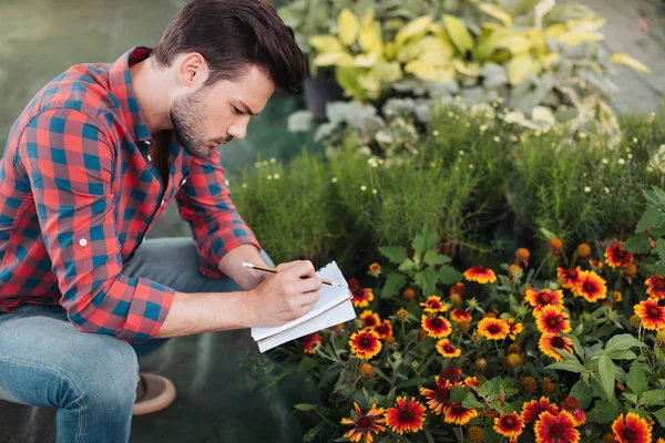 Gardener making notes in notebook — Stock Photo