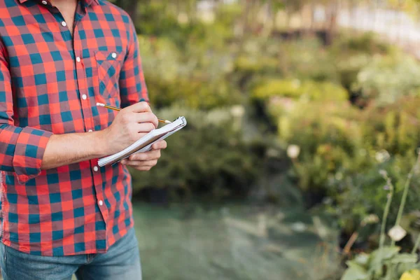 Gardener making notes in notebook — Stock Photo