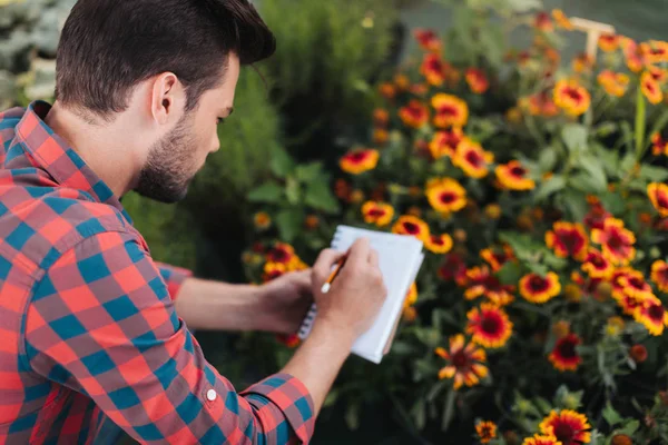 Gärtner macht sich Notizen in Notizbuch — Stockfoto