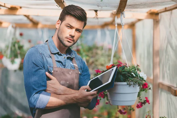 Gardener with tablet in greenhouse — Stock Photo