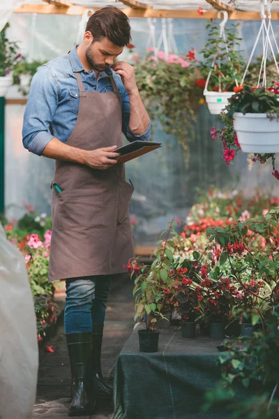 Jardineiro em avental com tablet — Fotografia de Stock