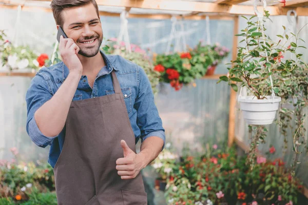 Gardener talking on smartphone in greenhouse — Stock Photo