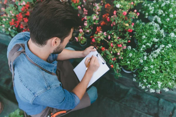 Jardineiro fazendo anotações durante o trabalho — Fotografia de Stock