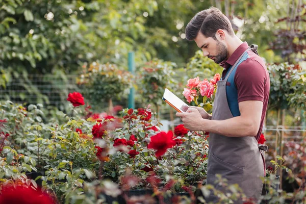 Giardiniere con tavoletta durante lavoro in giardino — Foto stock