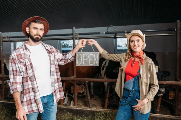 Farmers with open sign in cowshed — Stock Photo