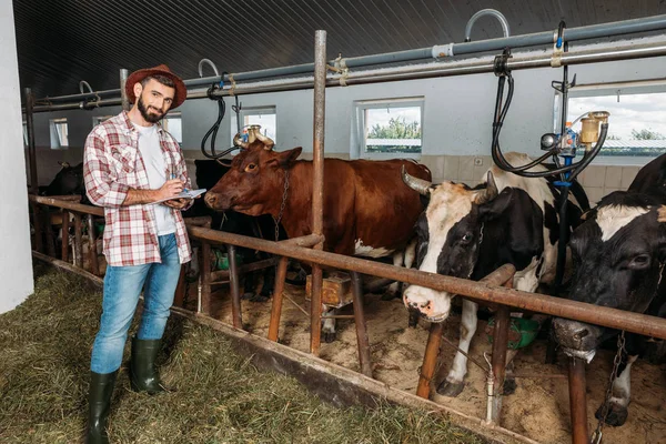 Bauer macht sich Notizen im Kuhstall — Stockfoto