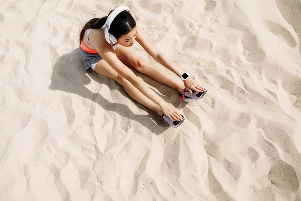 Sportlerin dehnt sich auf Sand — Stockfoto