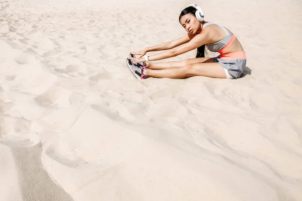 Спортсменка, растянувшаяся на песке — стоковое фото