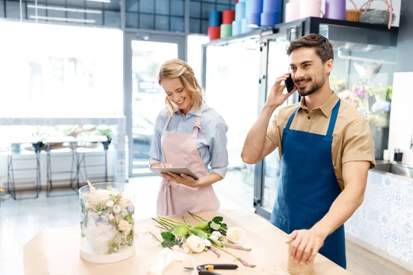 Floristas que trabajan con dispositivos digitales - foto de stock