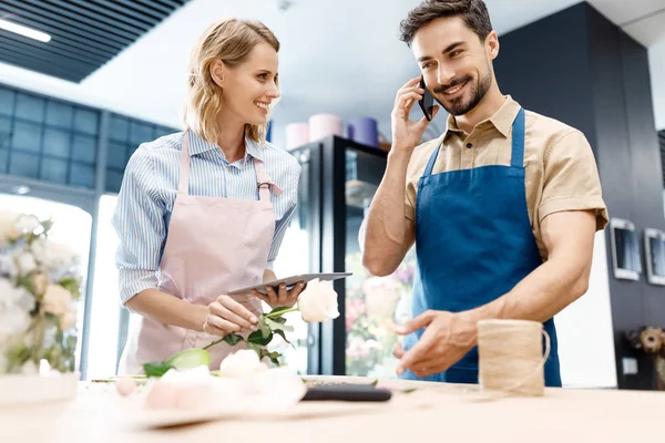 Floristas que trabajan con dispositivos digitales - foto de stock